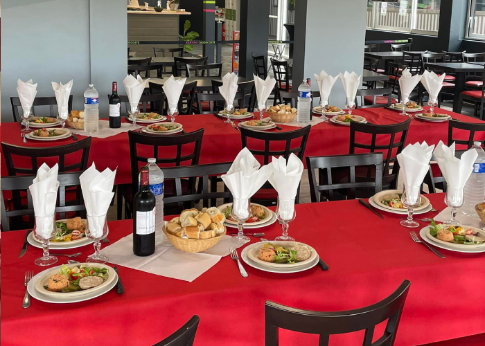 Salle de repas avec nappes rouges et service complet dressé par Traiteur Péberat Cédril