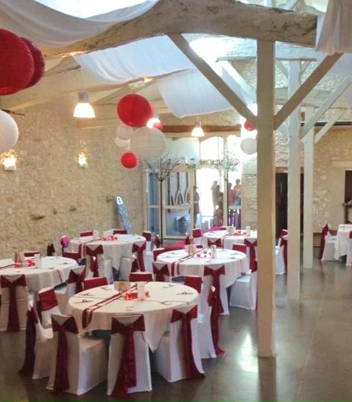 Salle de réception en pierre décorée en rouge et blanc pour un mariage ou une fête privée