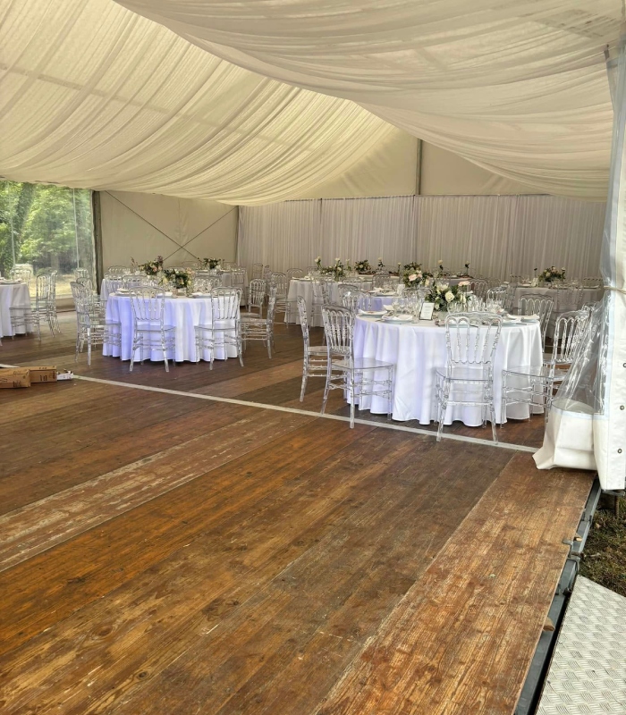 Salle de réception élégante sous chapiteau avec tables dressées pour un mariage ou un événement